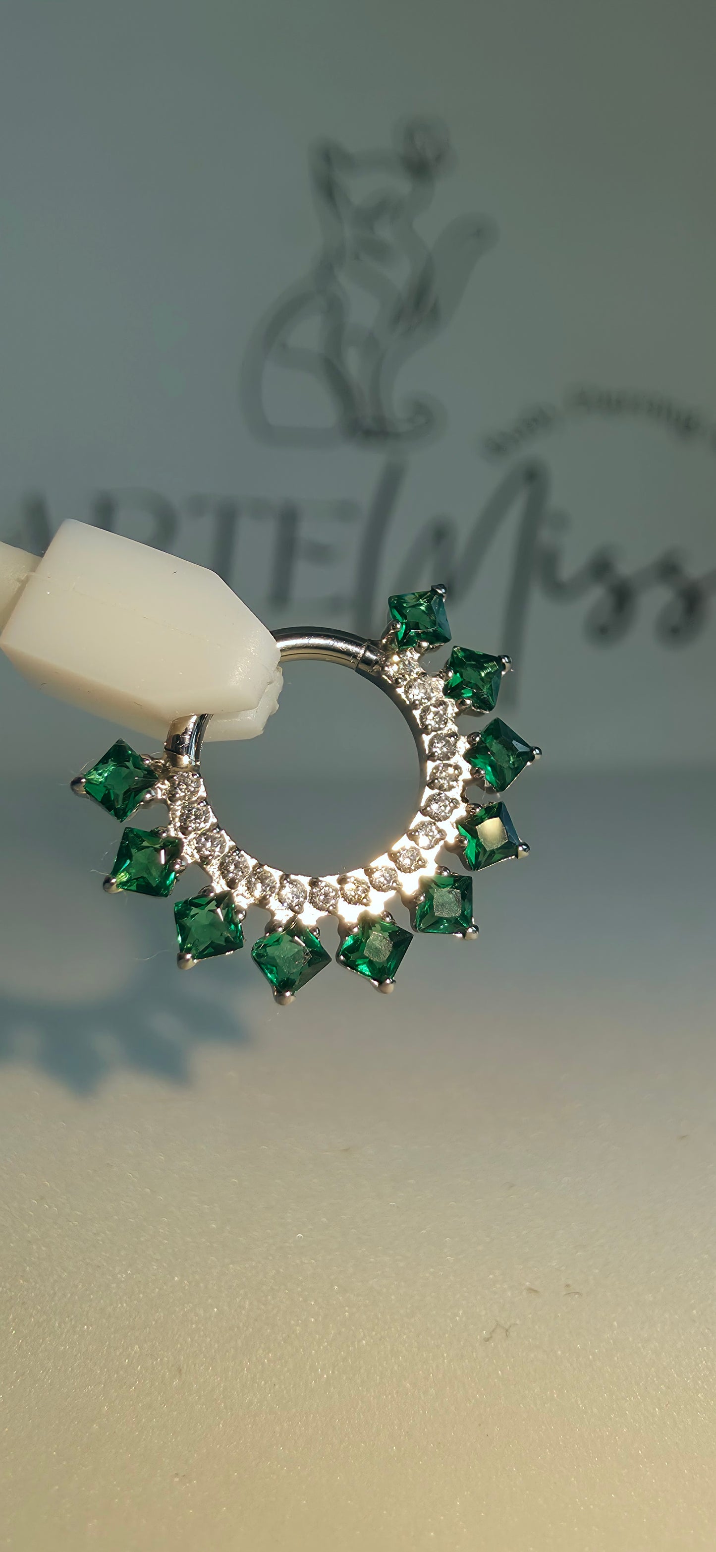 Clicker de Titanio con incrustaciones de zirconia color verde esmeralda.